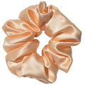 Light peach satin scrunchie on a light gray background