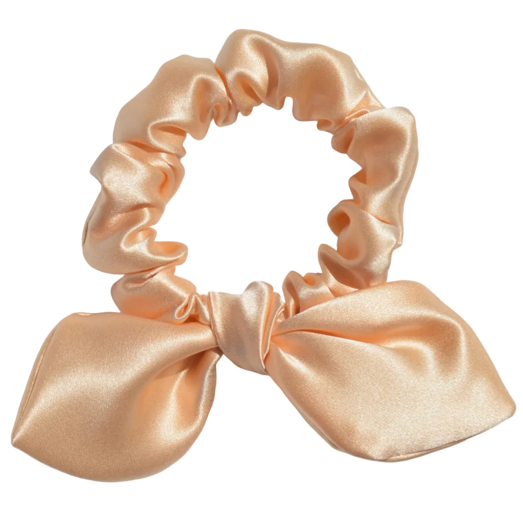 Pink satin scrunchie with a bow on a light gray background