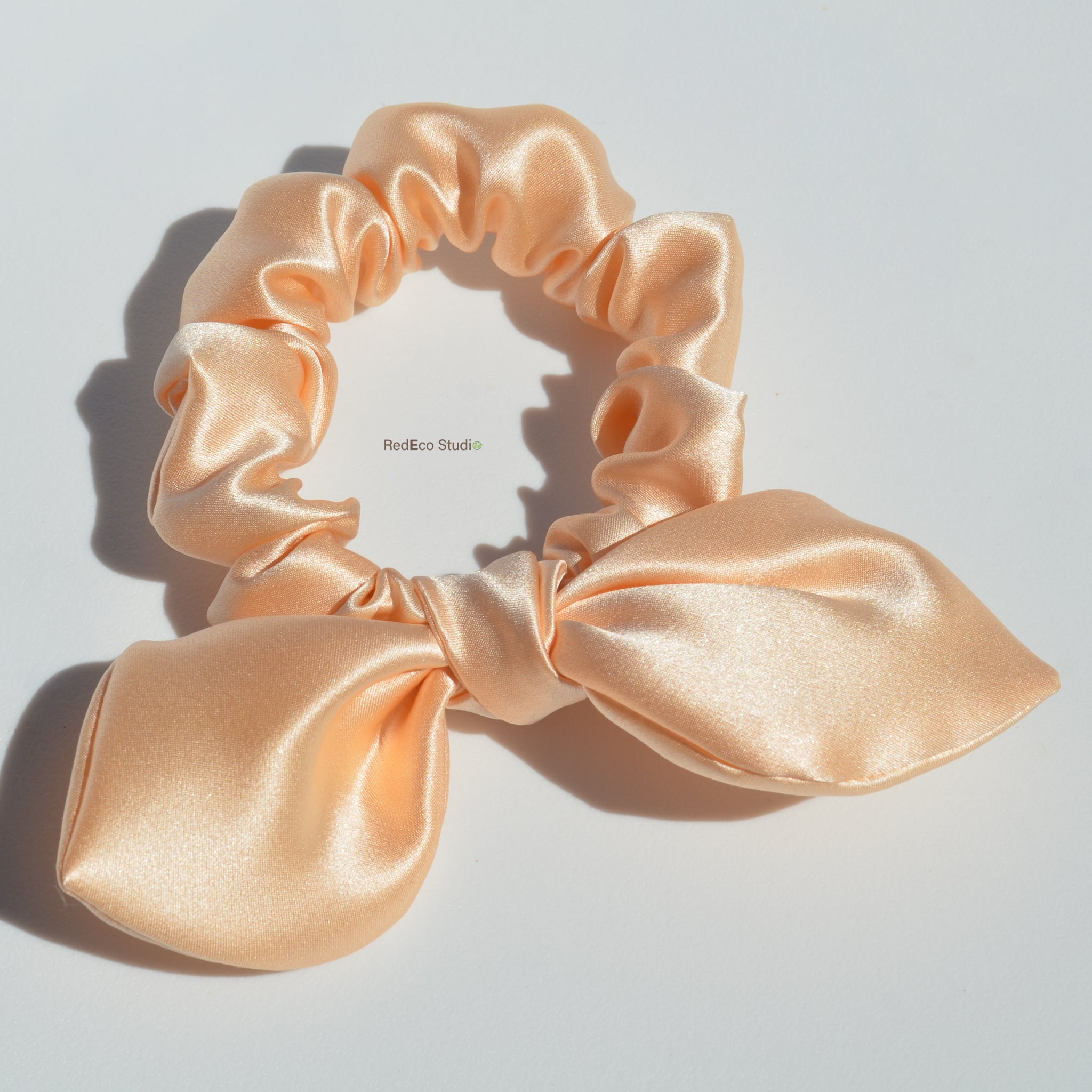 Pink satin scrunchie on a light gray background