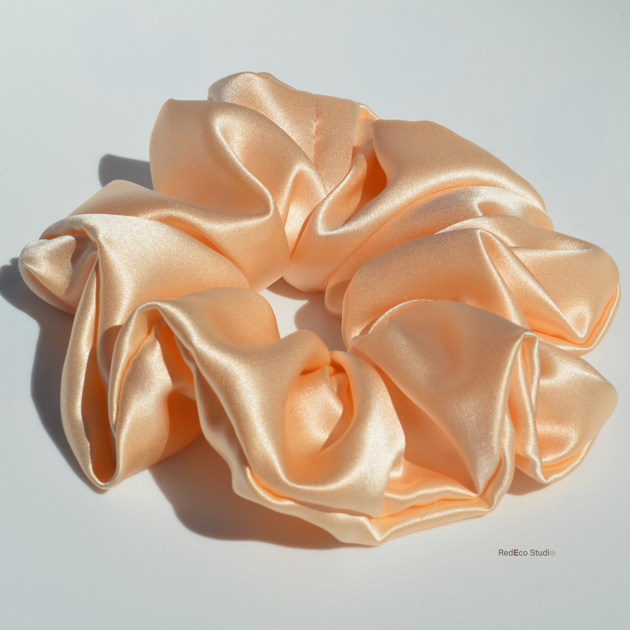 Large peach satin scrunchie on a light gray background