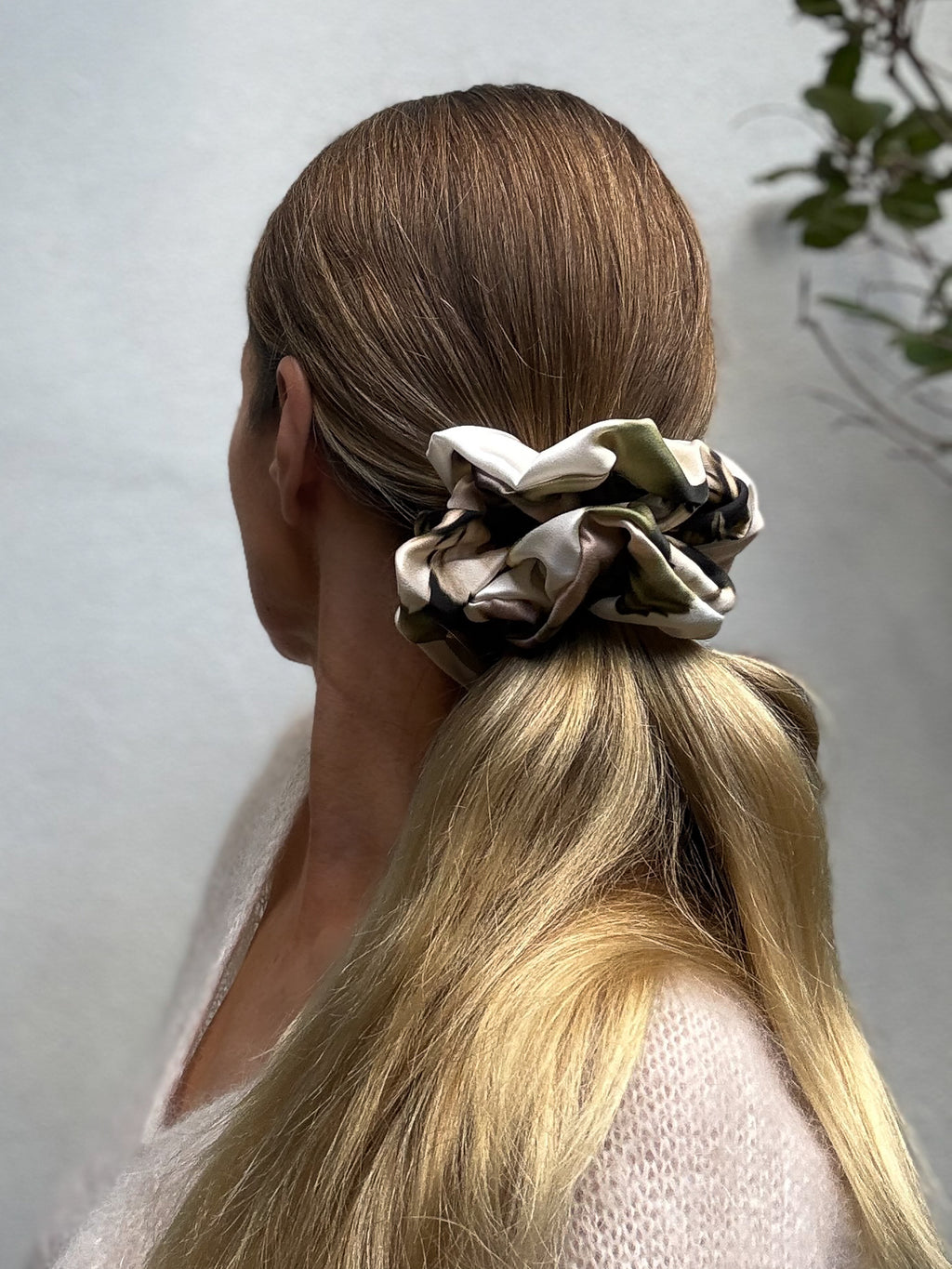 Person with an oversized scrunchie in their hair against a neutral background