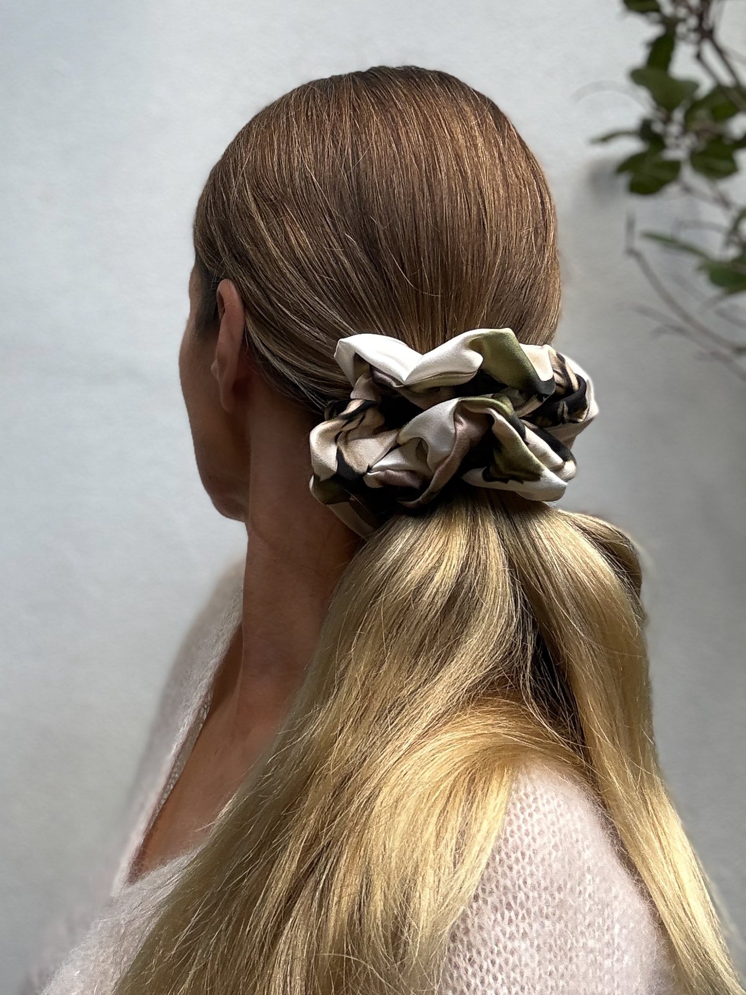 Person with an oversized scrunchie in their hair against a neutral background