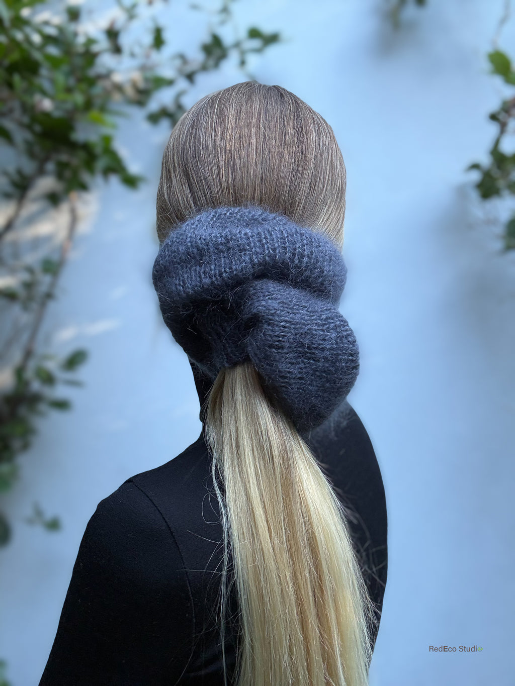 Person with a grey scrunchie in their hair against a blurred natural background