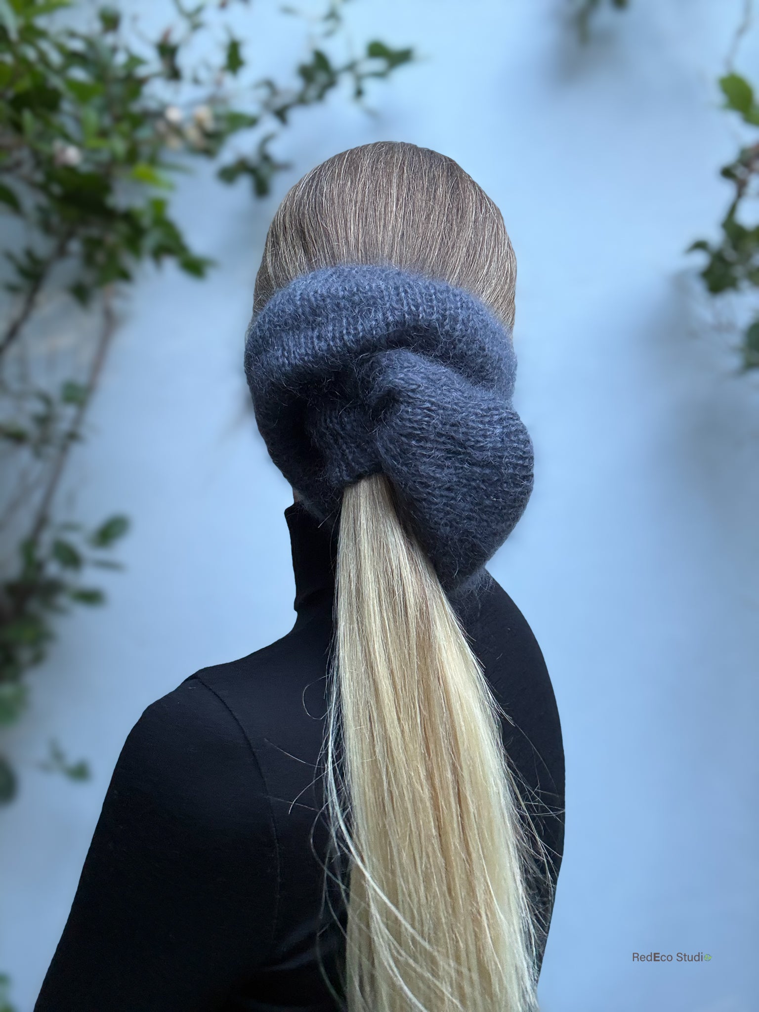 Person with a grey scrunchie in their blonde hair against a blurred natural background