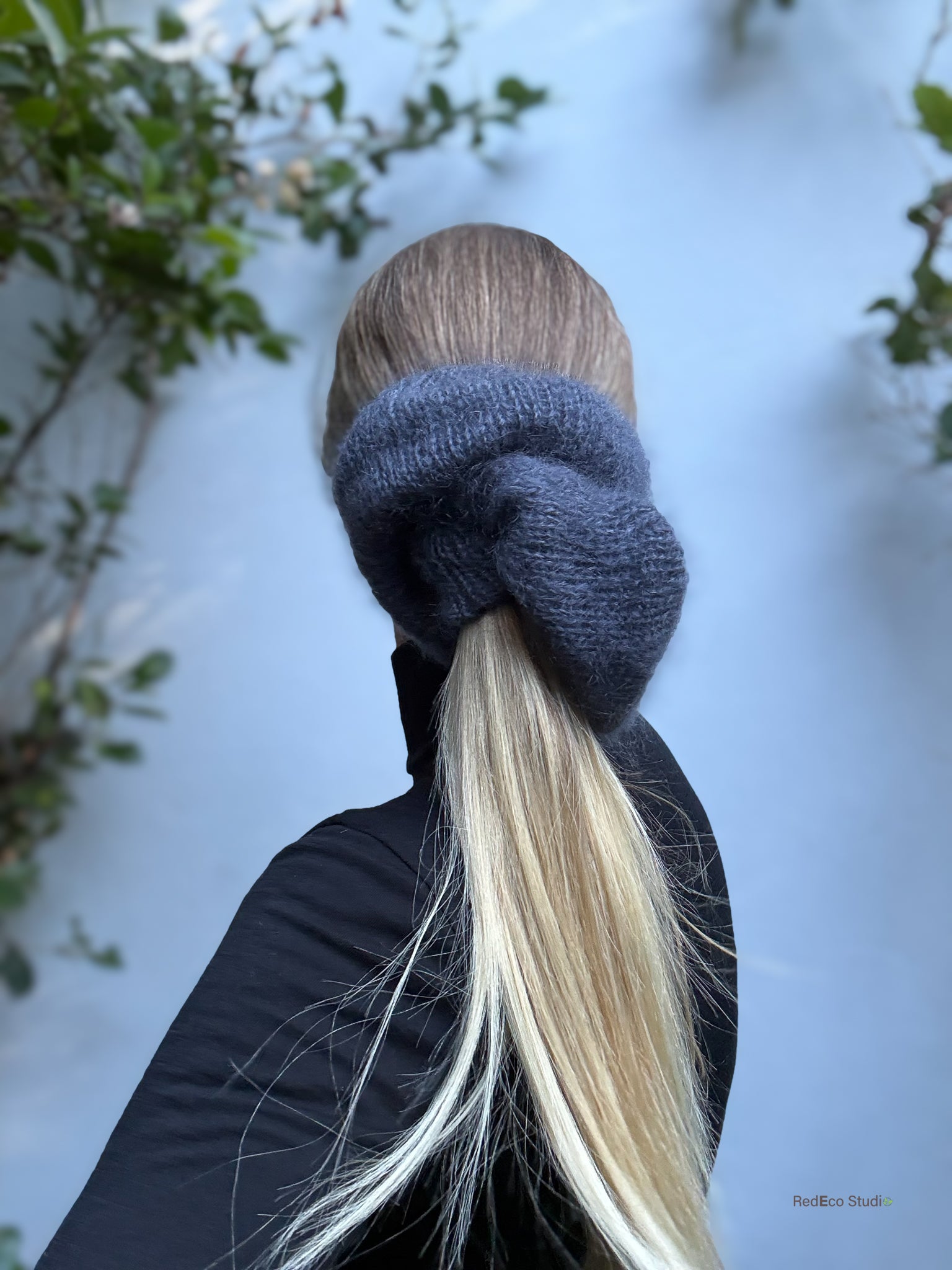 Close-up of a grey scrunchie on a blonde ponytail with a blurred natural background