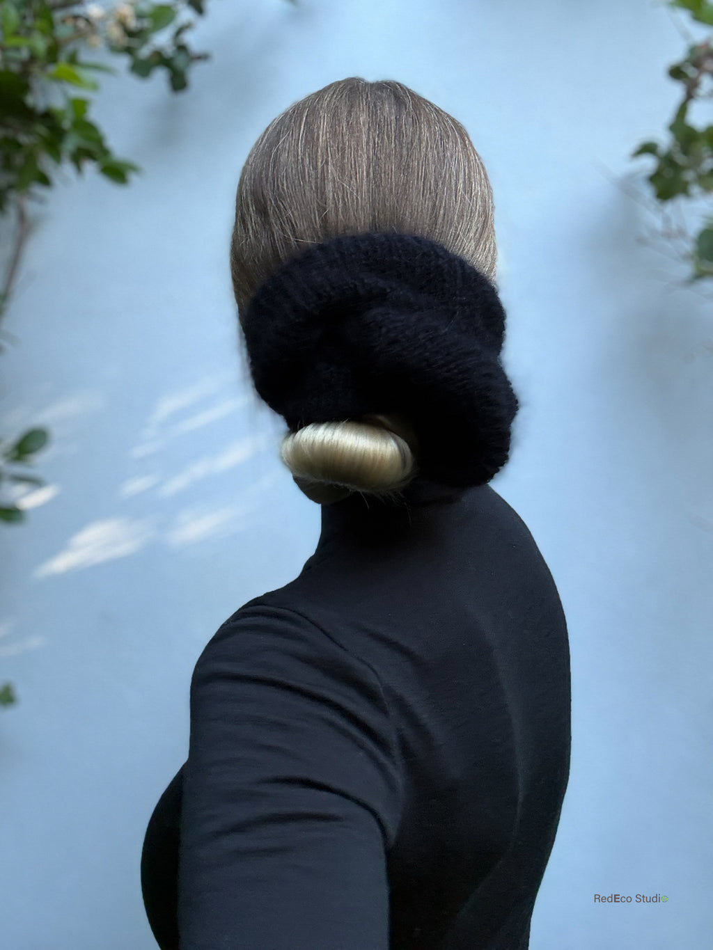 Person wearing a black knitted scrunchie against a light background