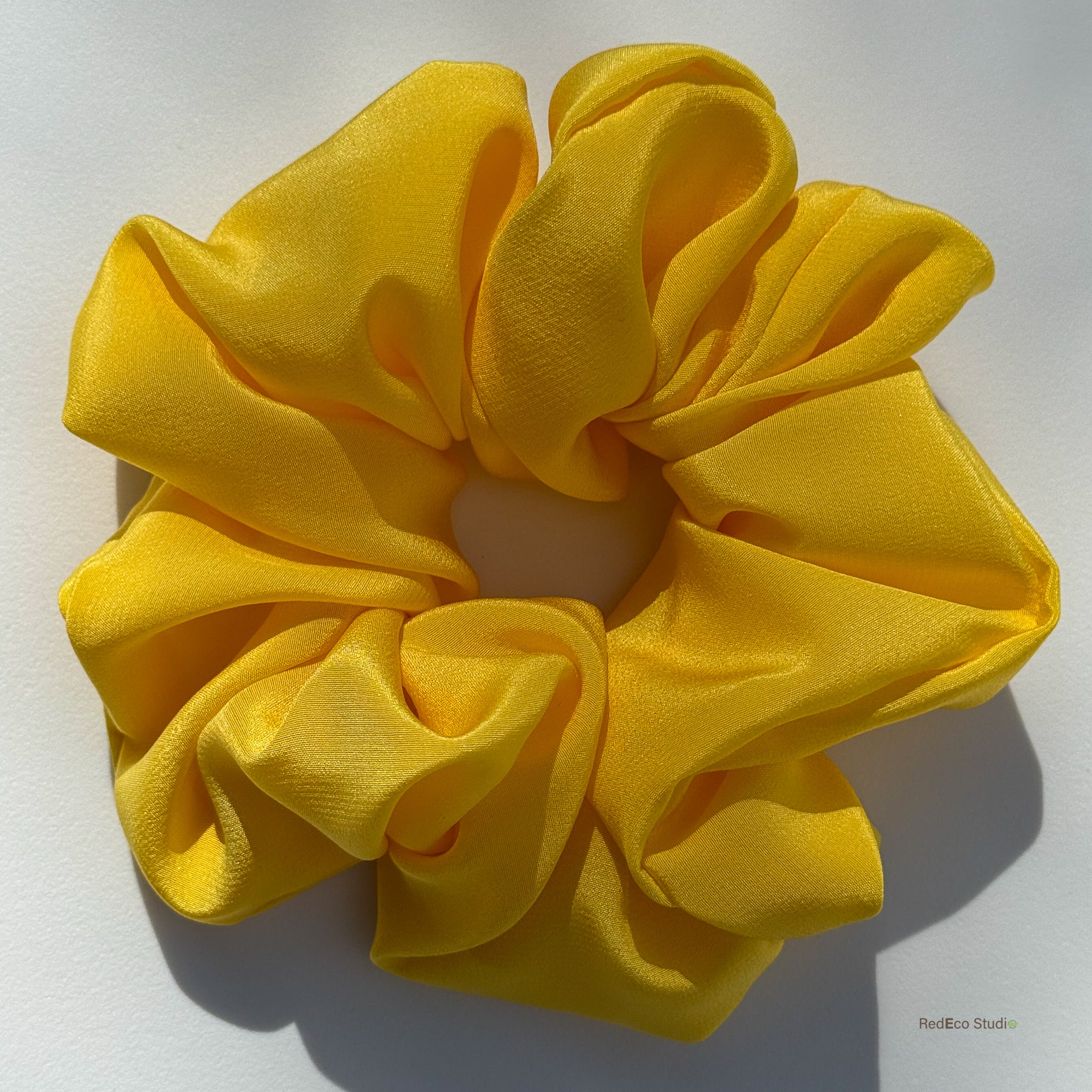 Large yellow silk scrunchie on a white background