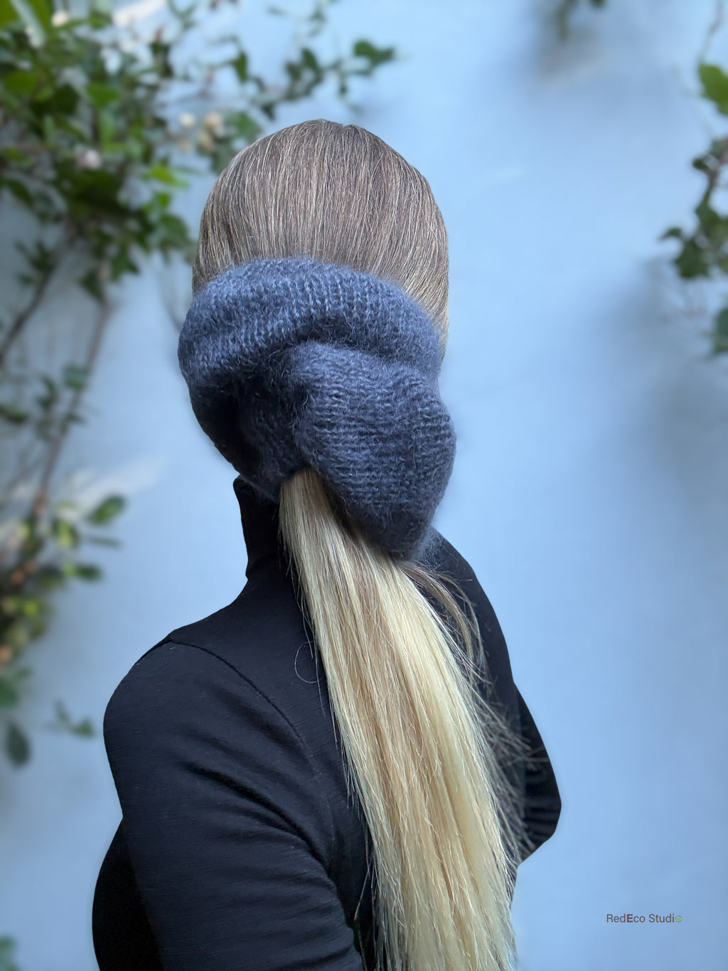 Person wearing a grey knitted scrunchie with a blurred natural background