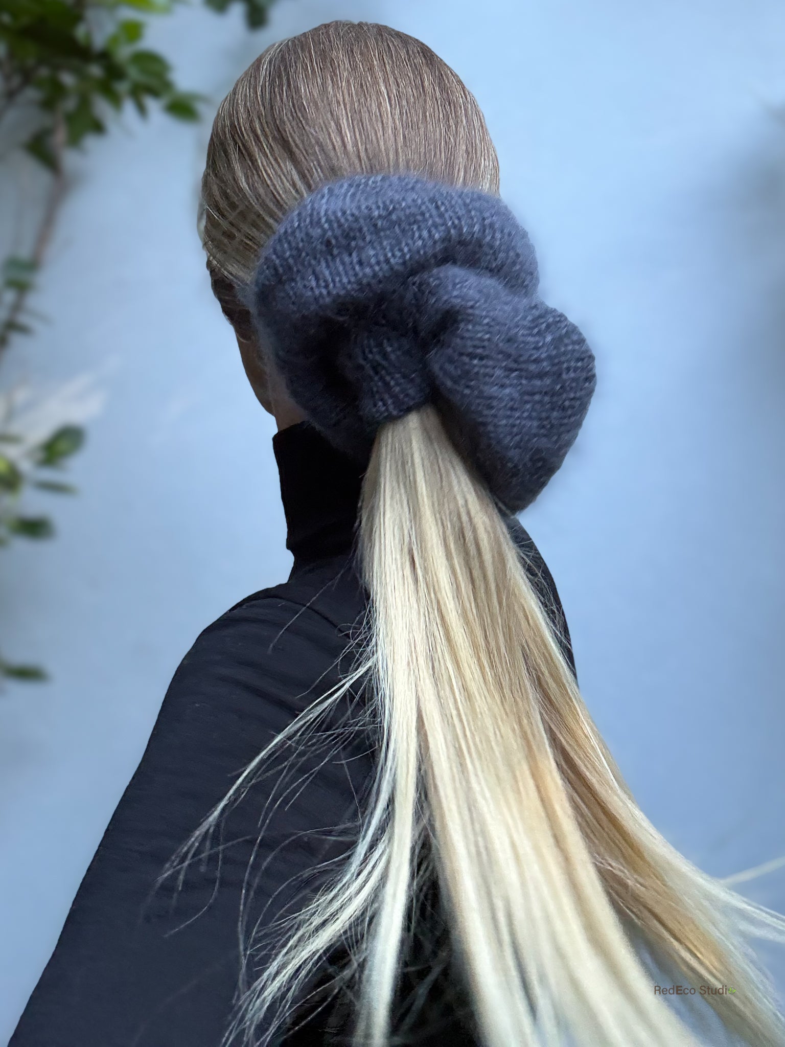 Person with a grey scrunchie in their hair against a blurred natural background