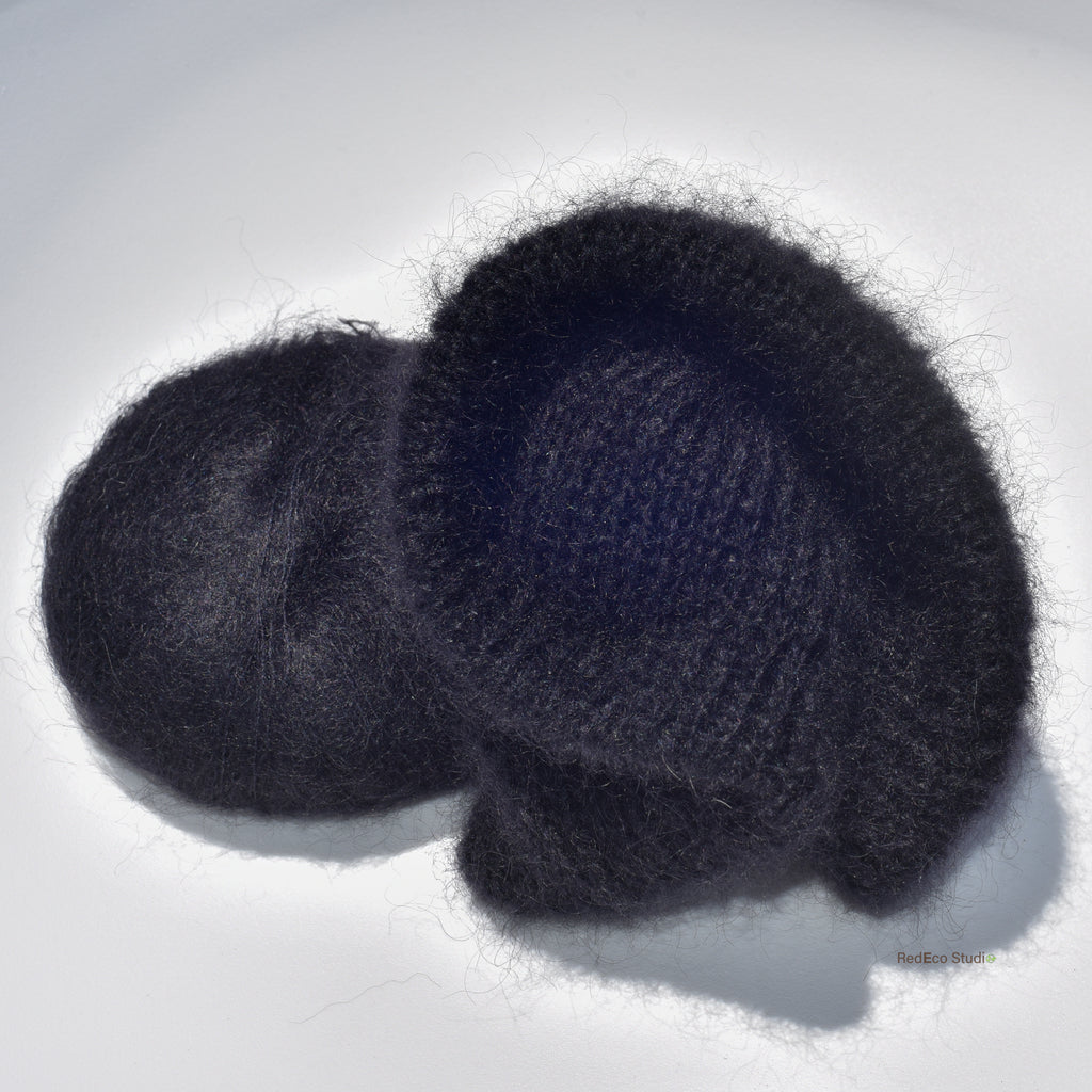 A black skein of yarn and a black knitted scrunchie on a white background