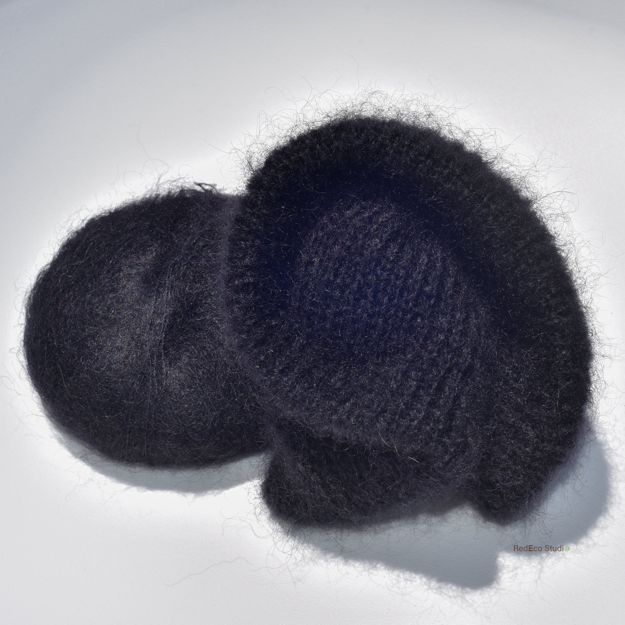 A black skein of yarn and a black knitted scrunchie on a white background