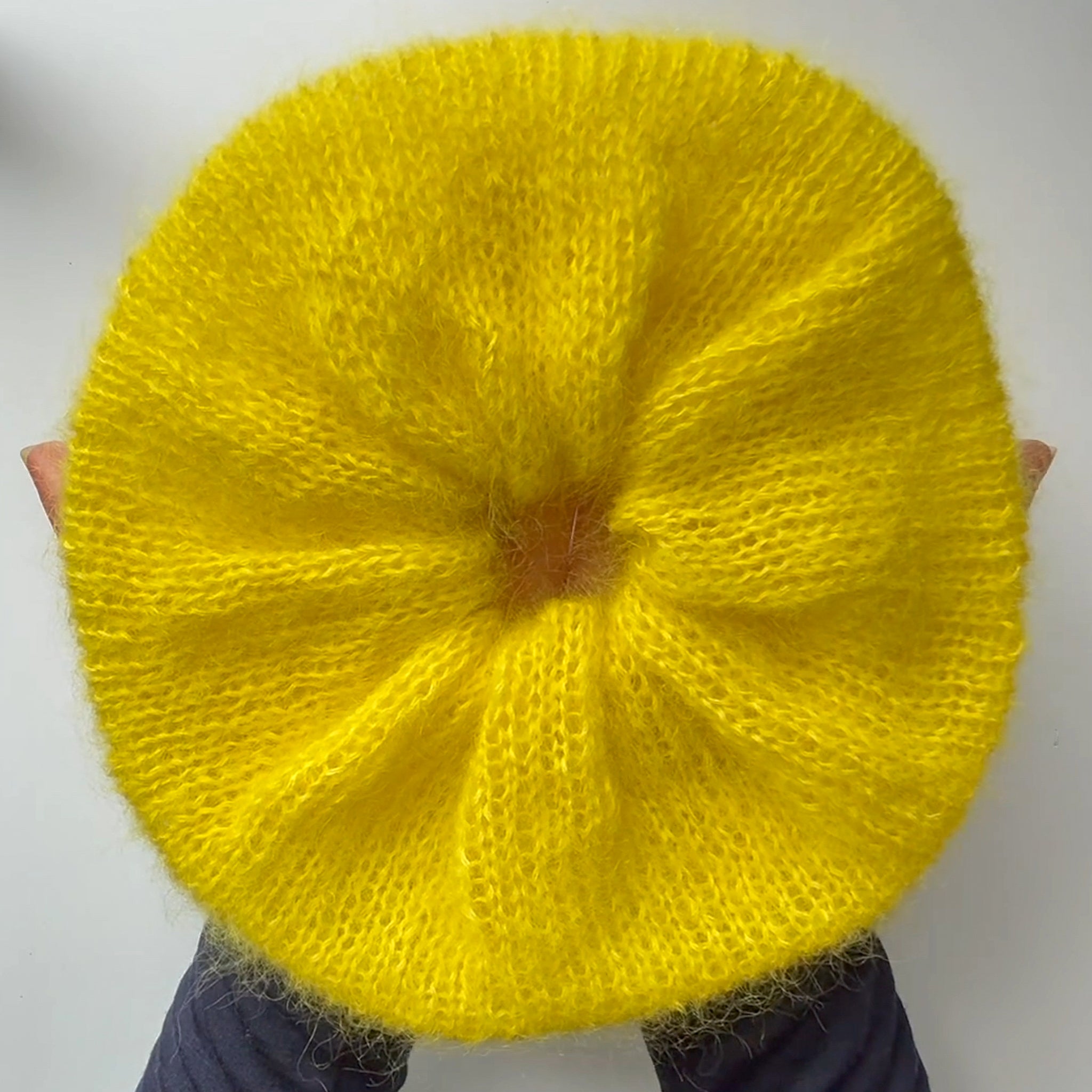 Hands holding large yellow knitted scrunchie 
