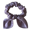 Purple scrunchie with a bow on a light background