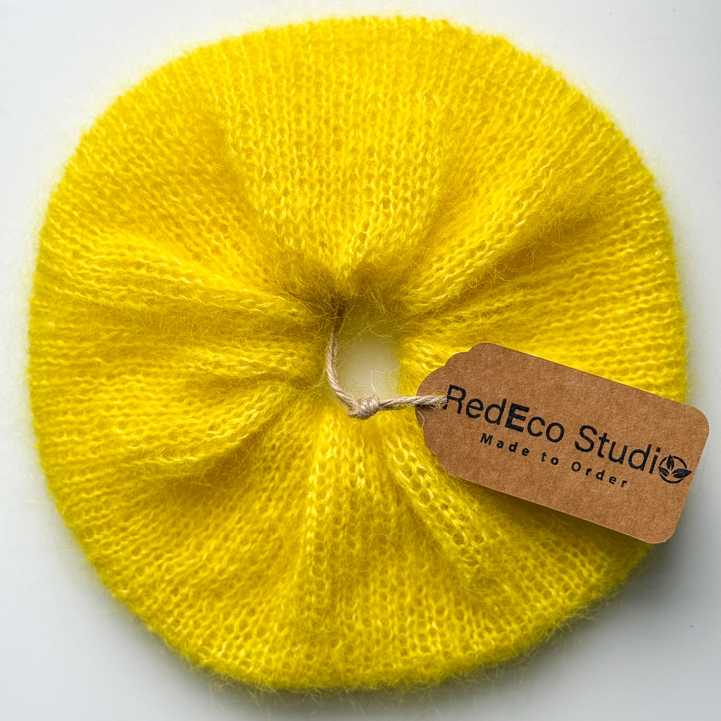 Oversized yellow hand-knitted scrunchie with RedEco Studio product tag attached.