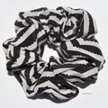 Black and white striped silk scrunchie on a light gray background