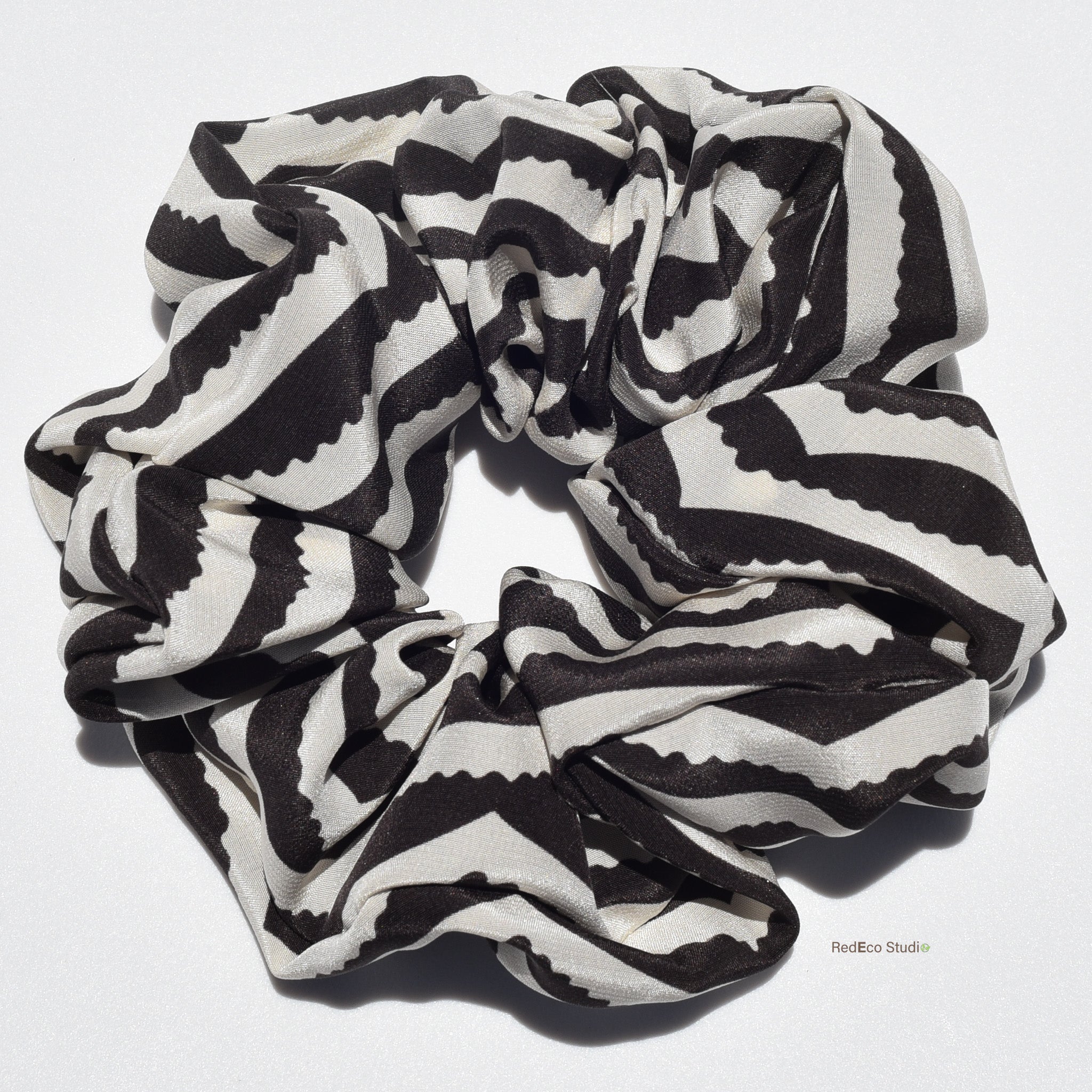 Black and white striped silk scrunchie on a light gray background