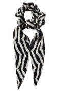 Black and white striped scrunchie on a light gray background