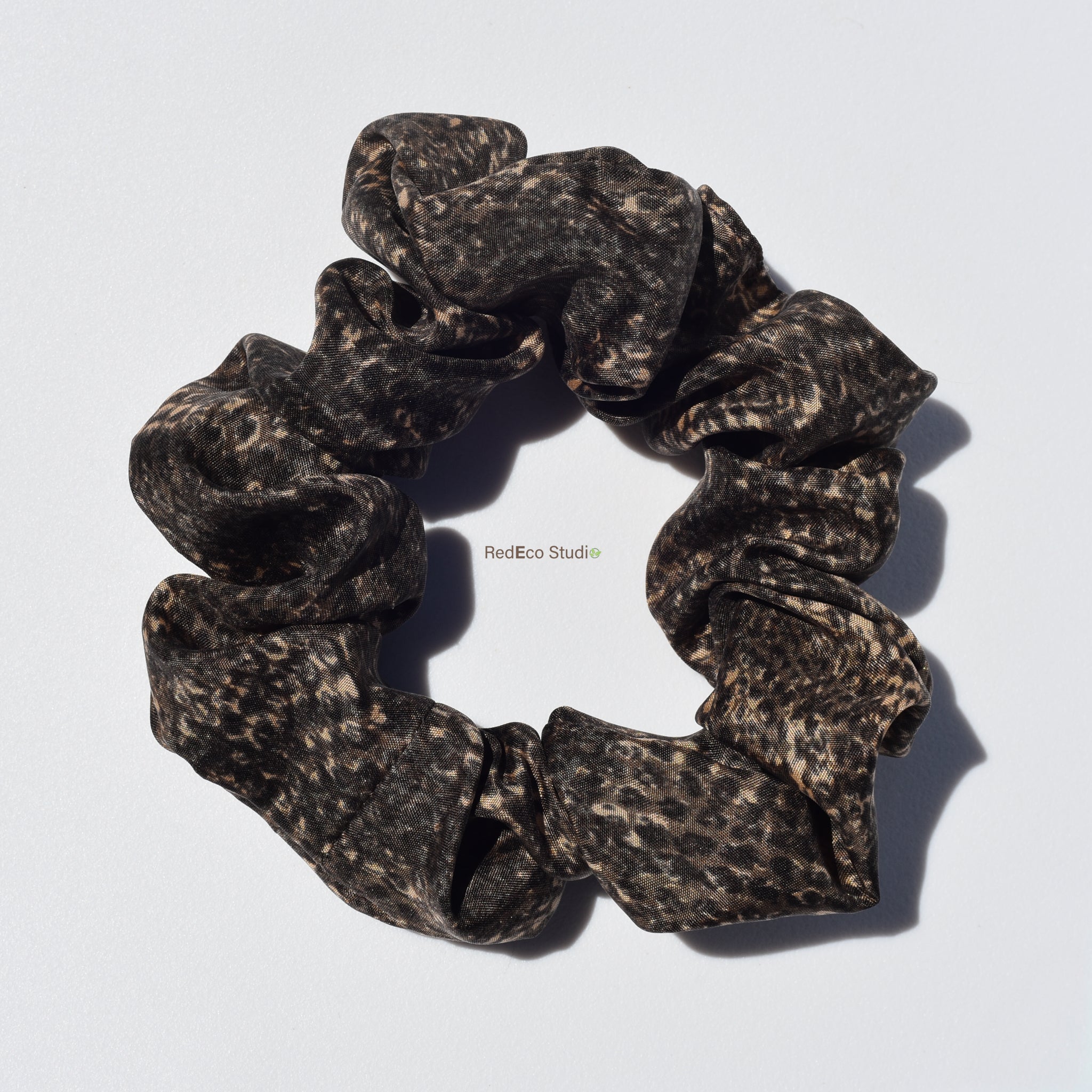 Silk scrunchie with brown snake print on a white background