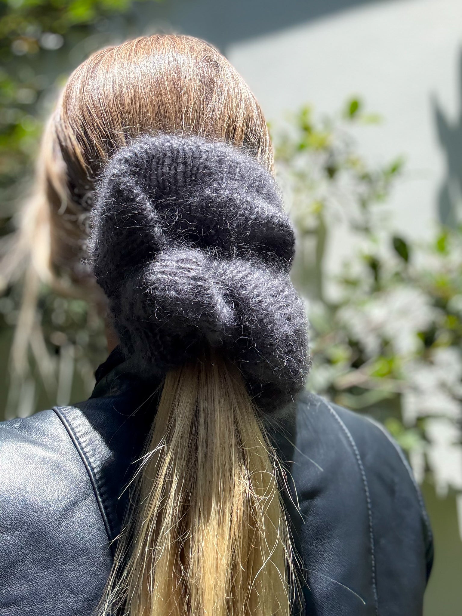 Person wearing a XL dark gray hand knitted scrunchie, standing outdoors.
