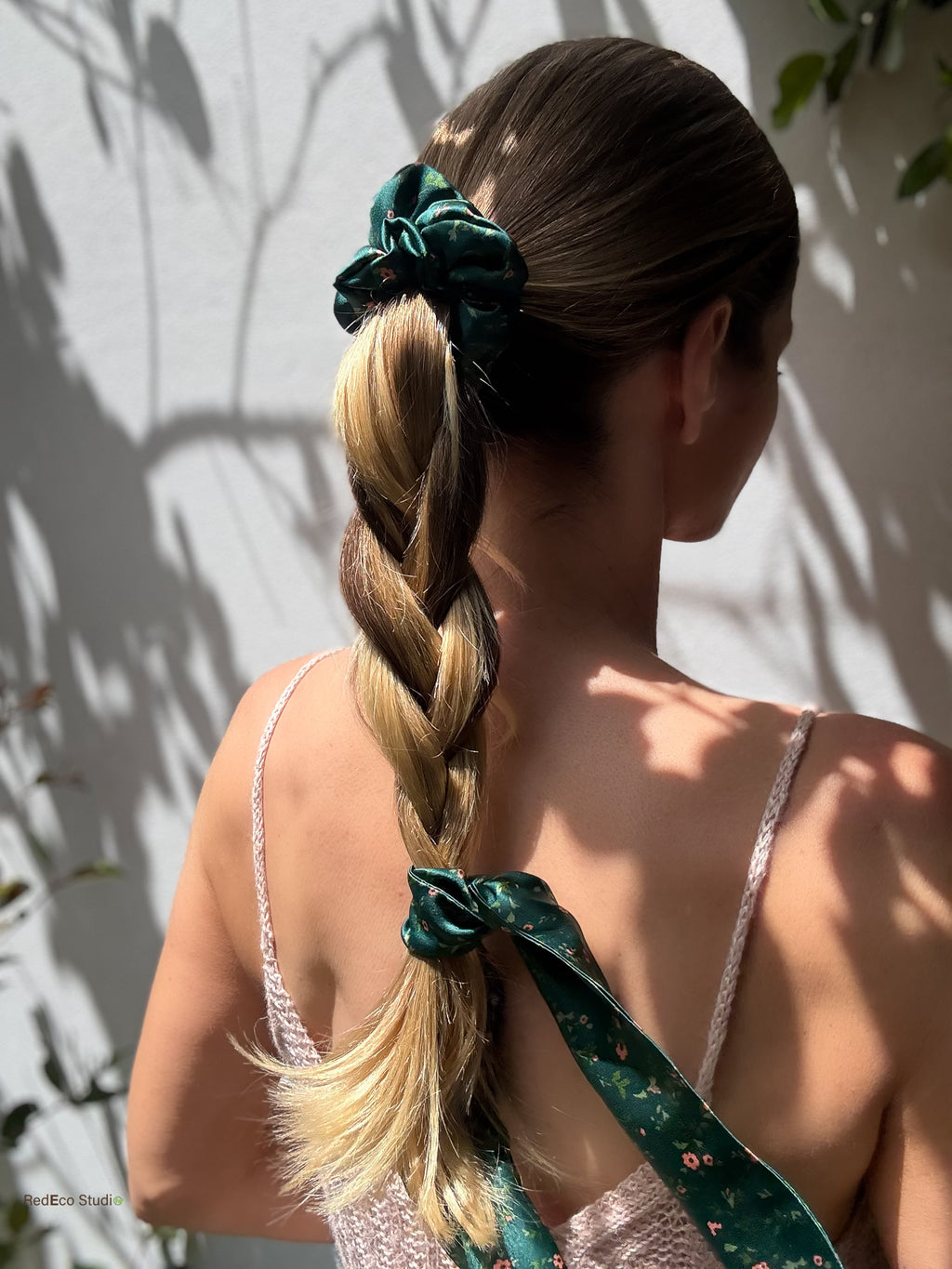 Emerald Posy silk scarf scrunchie on a high ponytail, with the tail tied at the end of a loose braid, back view in sunlight