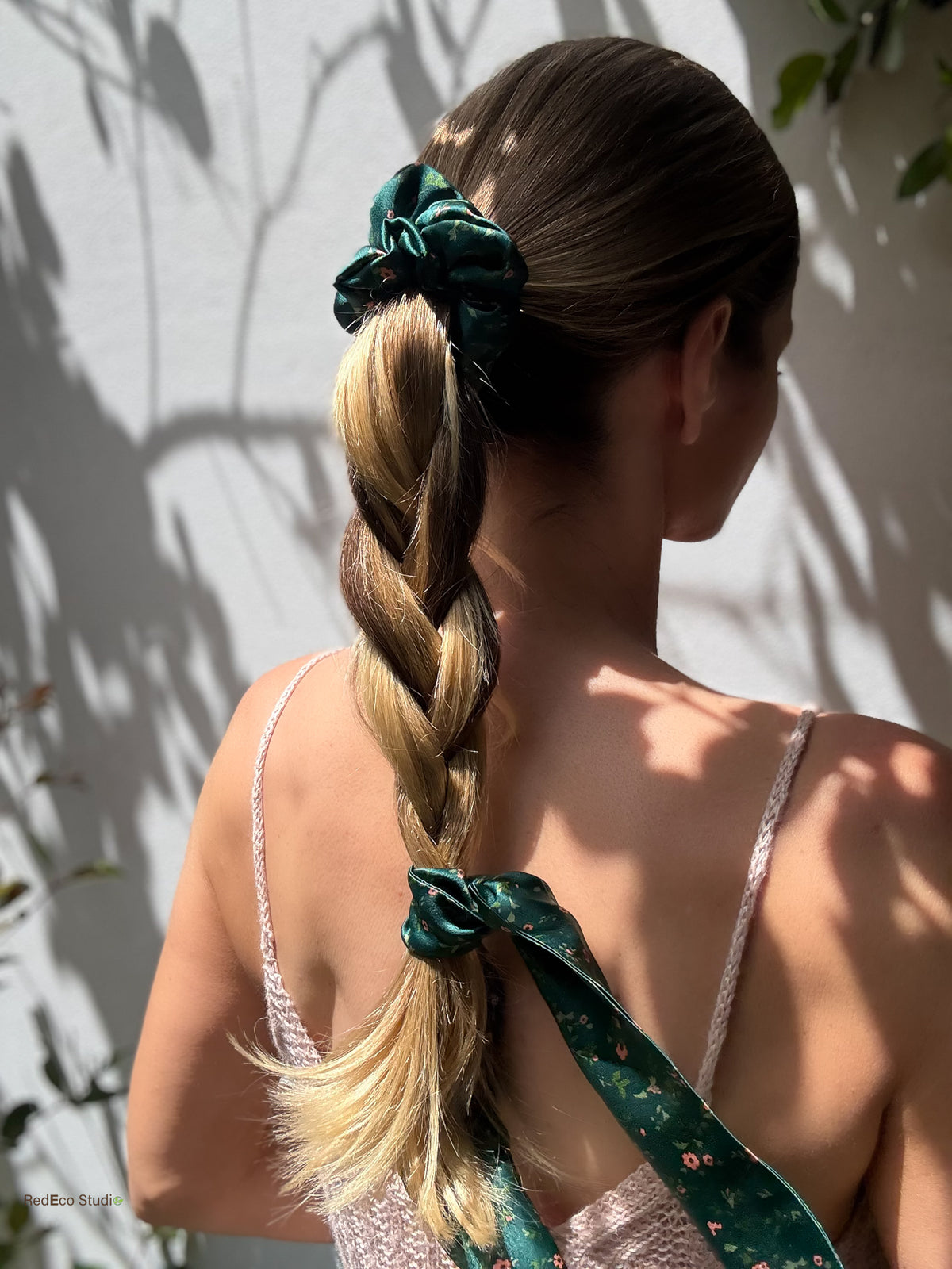 Emerald Posy silk scarf scrunchie on a high ponytail, with the tail tied at the end of a loose braid, back view in sunlight
