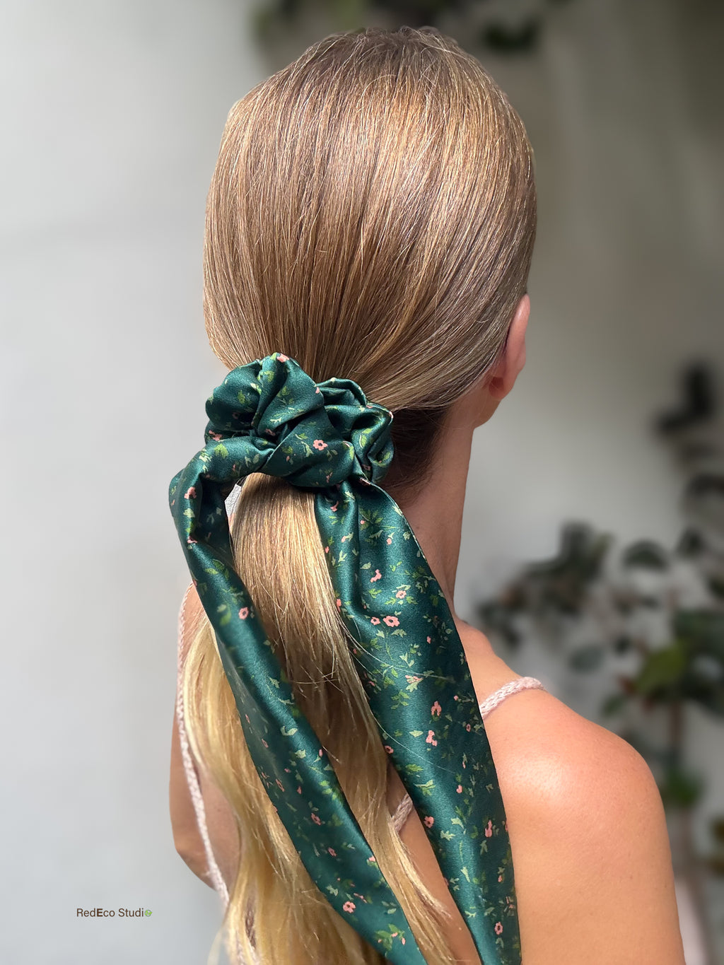 Emerald Posy silk scarf scrunchie on a sleek low ponytail, with its long floral tails trailing down, back view