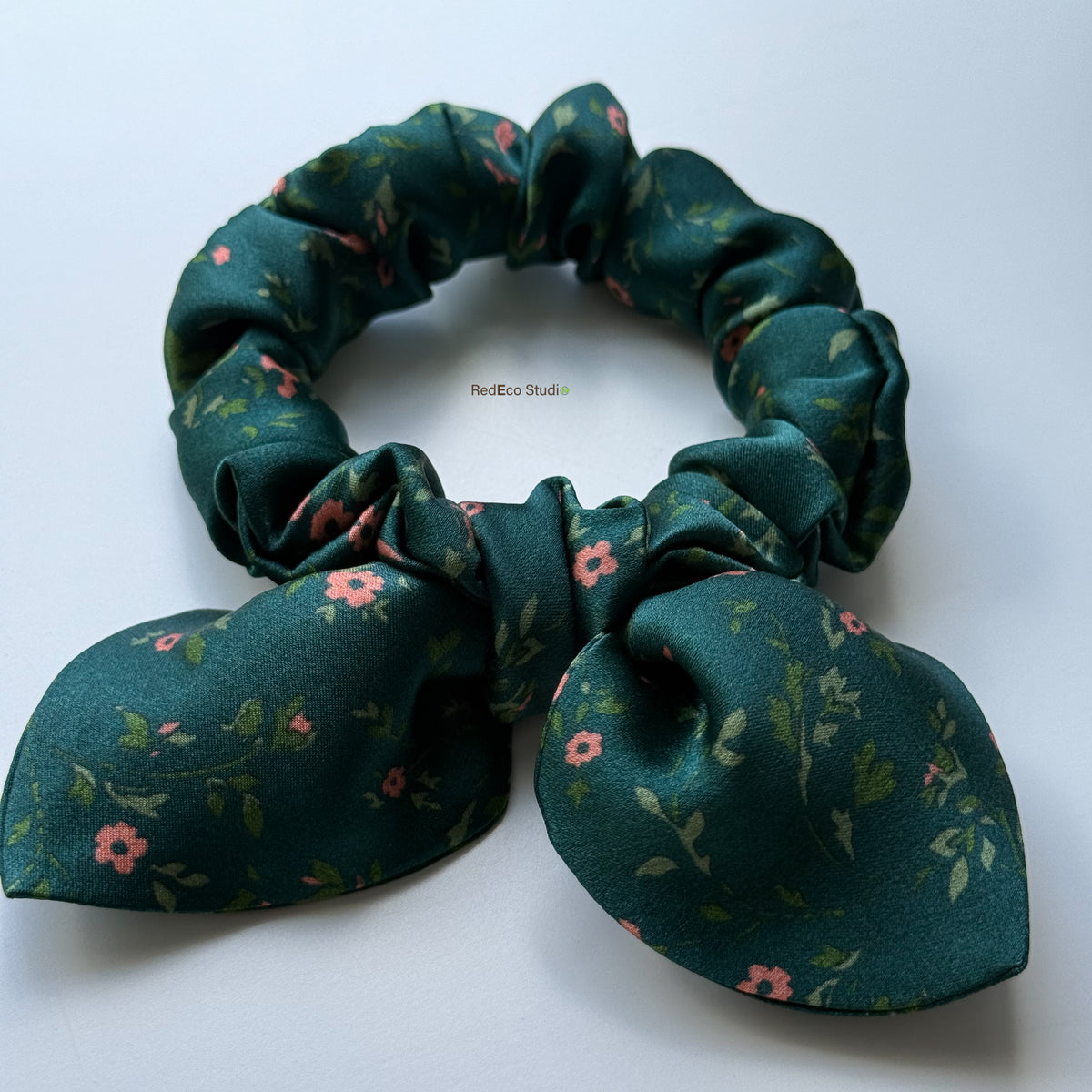 Close-up of the Emerald Posy mini scrunchie’s bow, showing the silk satin sheen and coral floral print