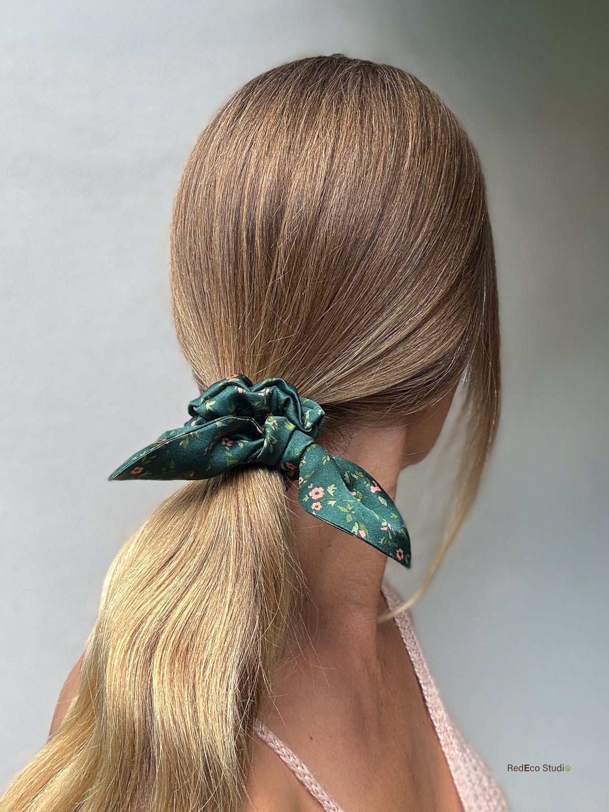 Emerald Posy mini silk bow scrunchie tied on a sleek low ponytail, back view