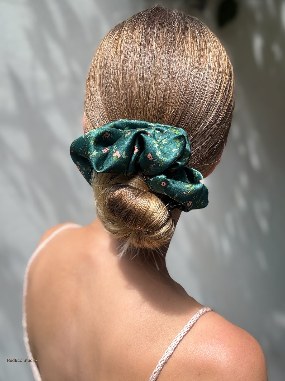 Emerald Posy oversized silk scrunchie on a low bun, back view in soft sunlight
