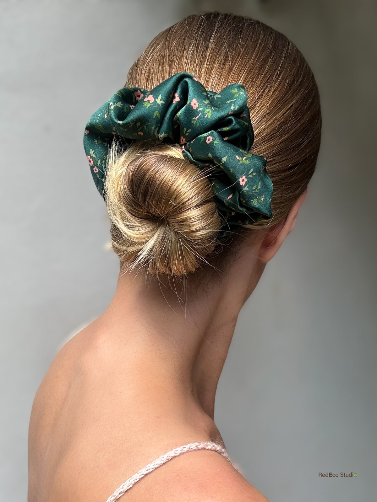 Emerald Posy oversized silk scrunchie wrapped around a low bun, side view, emerald green with coral flowers