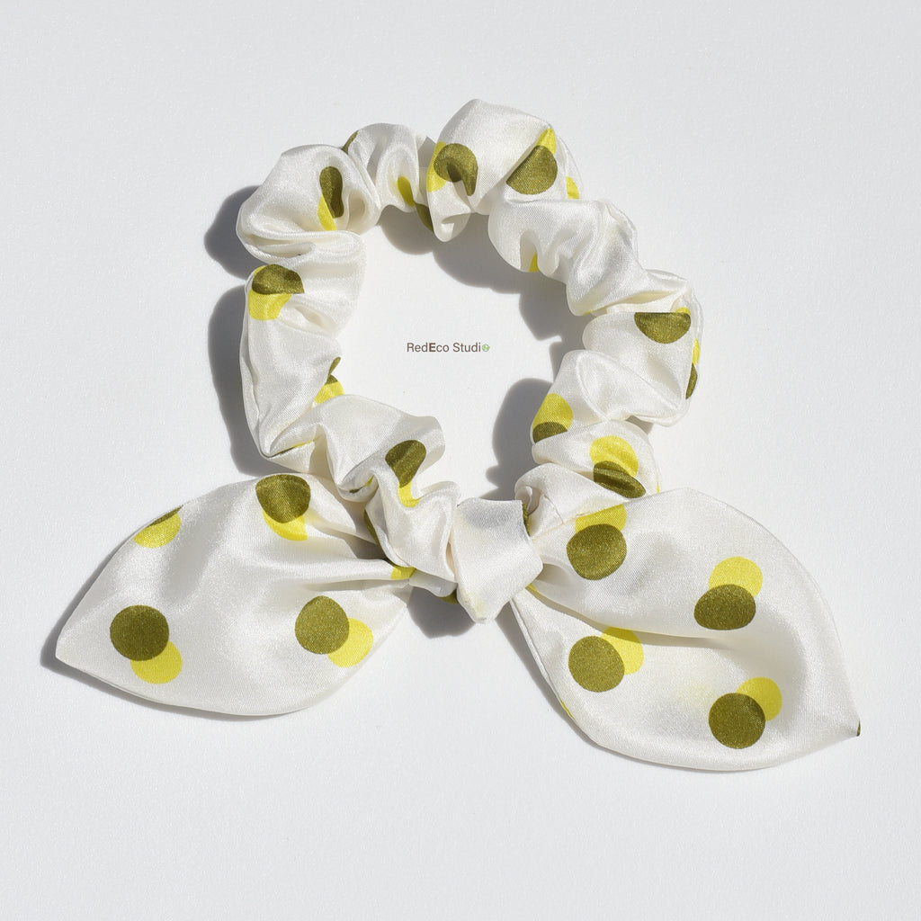 White mini premium silk bow scrunchie with green polka dots on a white background