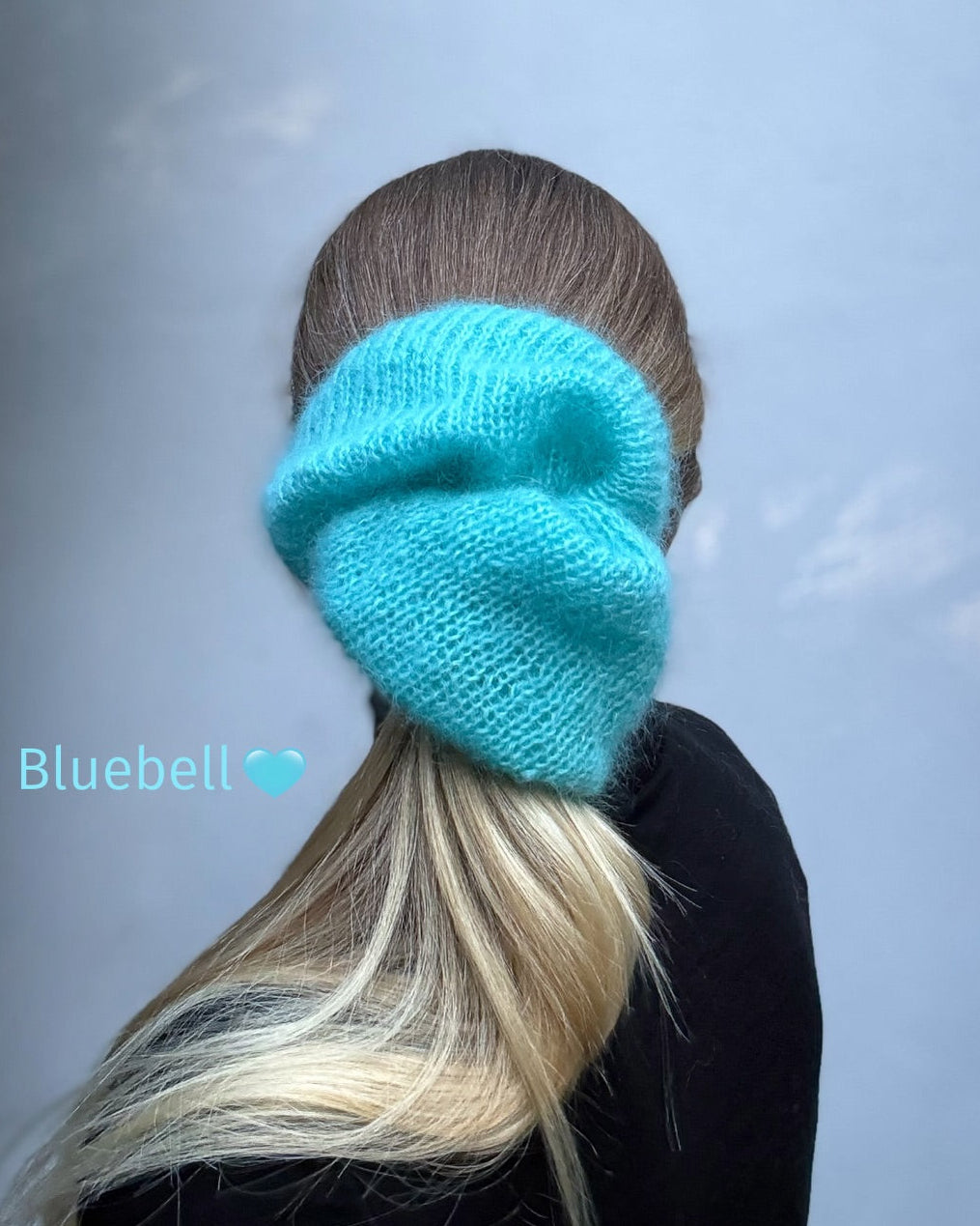A person shown from the back wearing a bright turquoise knit hair tie or hair accessory, with long blonde-highlighted hair visible against a pale blue-gray background. The text 'Bluebell' appears on the left.