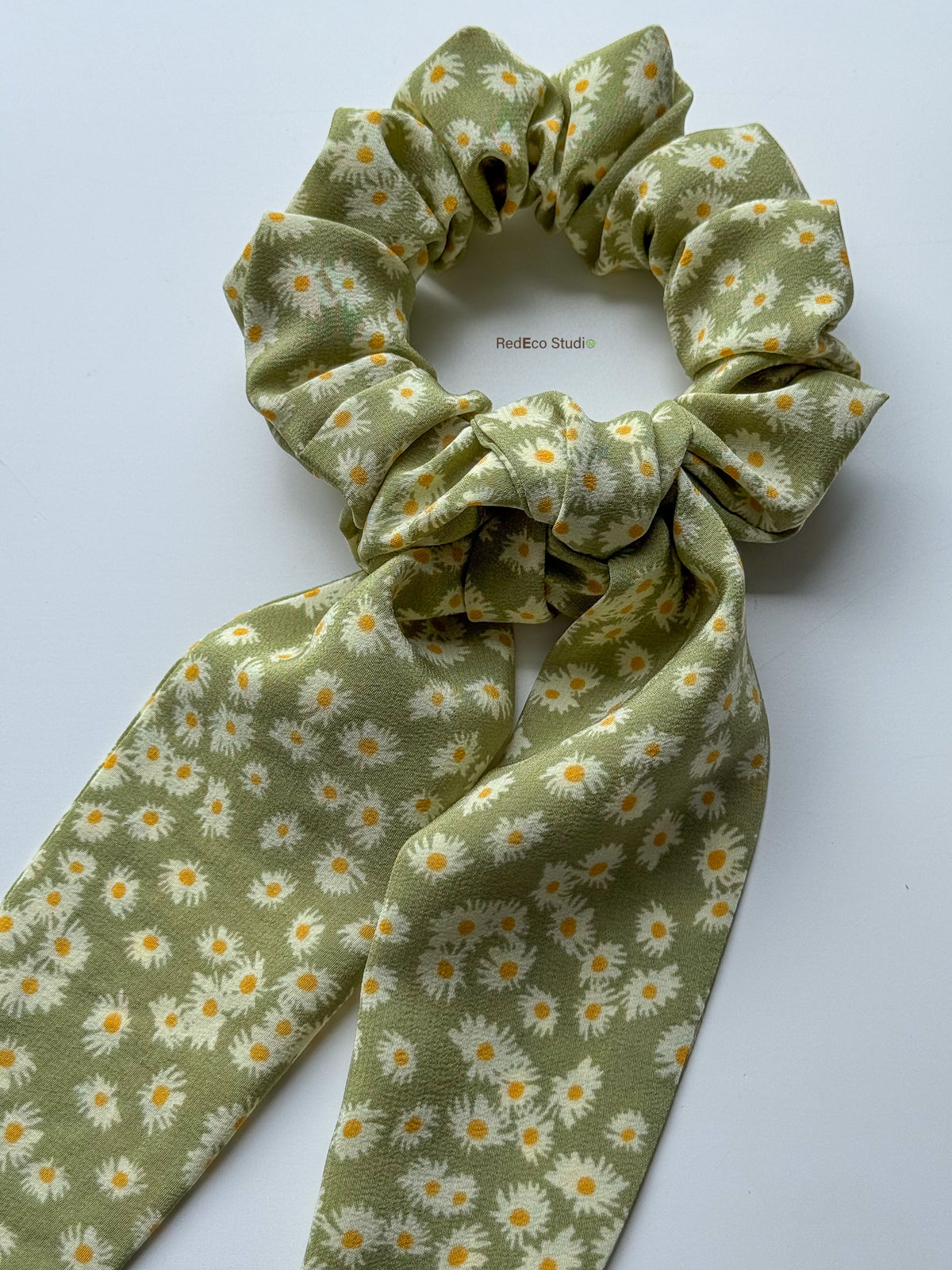 Close-up of the Matcha Daisy silk crêpe de chine scrunchie with its long tails tied in a knot