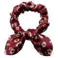Merlot Daisy mini silk bow scrunchie, flat lay top view showing cream daisies with rust-orange centres on burgundy satin