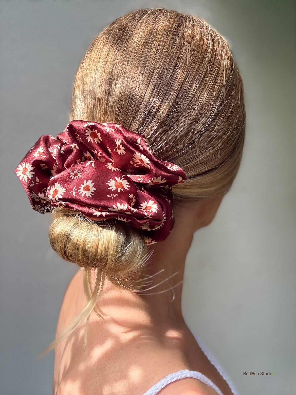 Merlot Daisy oversized silk scrunchie wrapped around a low bun, side view showing the burgundy daisy print and satin sheen