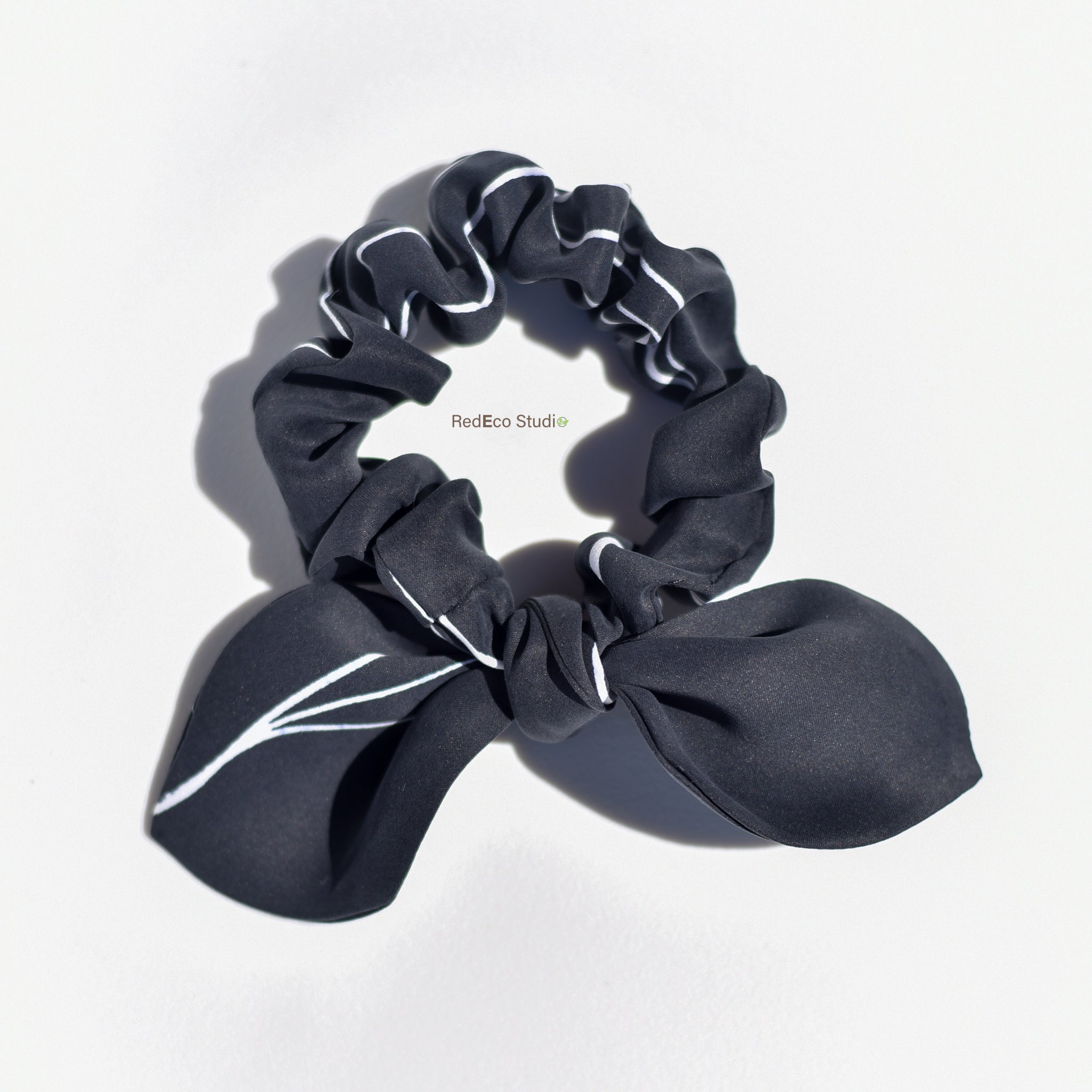 Black silk scrunchie with bow on a white background