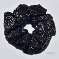 Large black silk scrunchie with white speckles on a light gray background