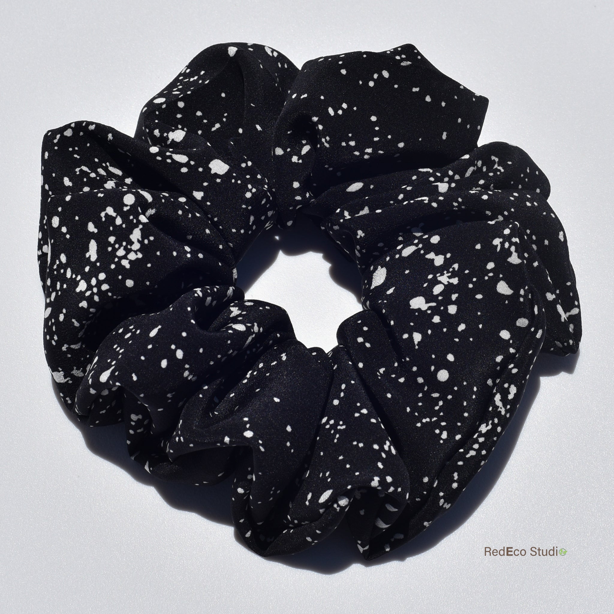 Large black silk scrunchie with white speckles on a light gray background