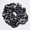 Large leopard patterned silk scrunchies on a white background