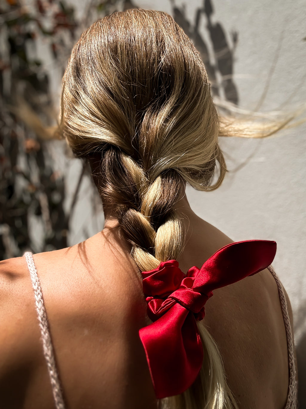 Braided hair with a red ribbon against a neutral background