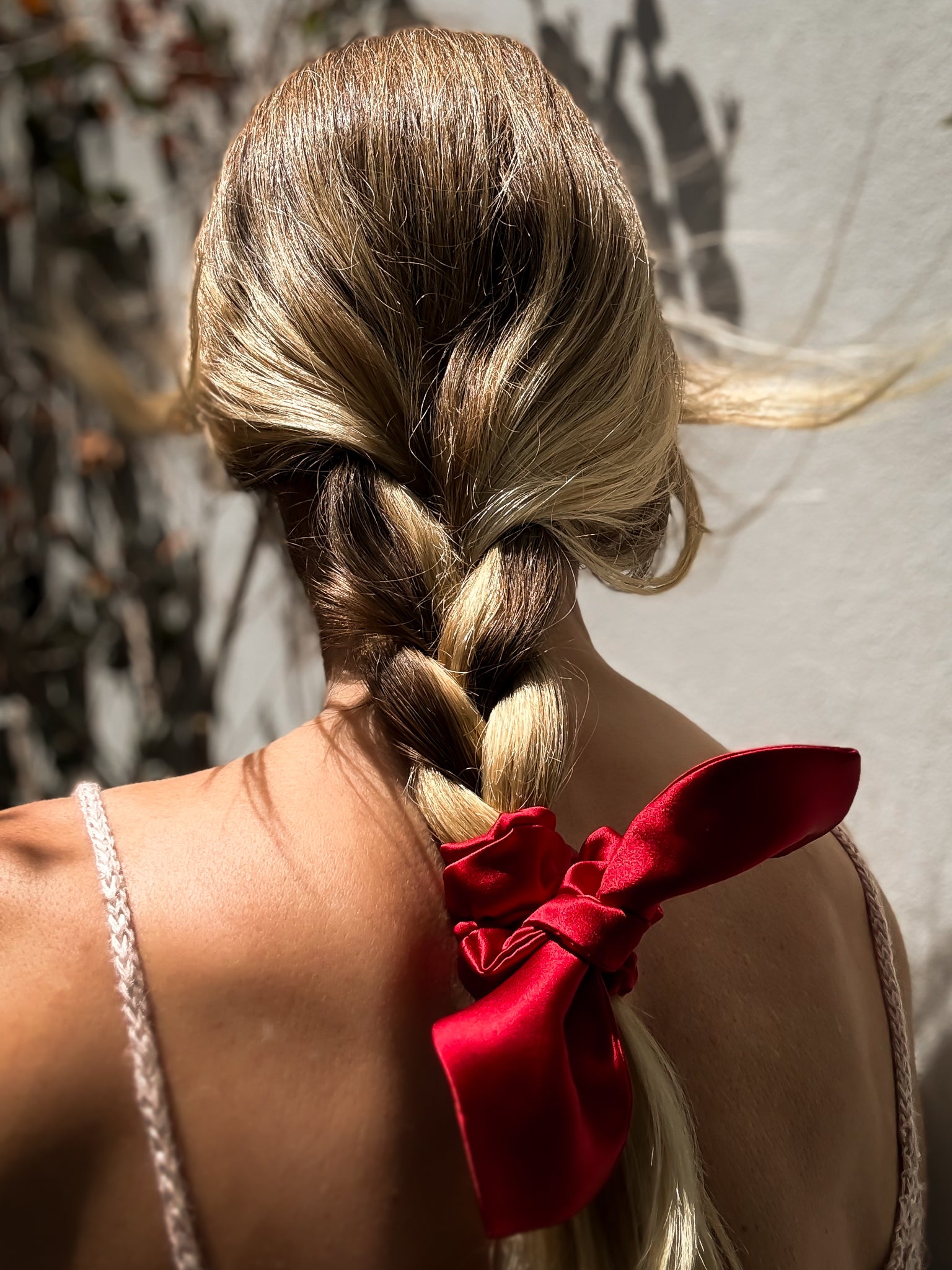 Braided hair with a red ribbon against a neutral background