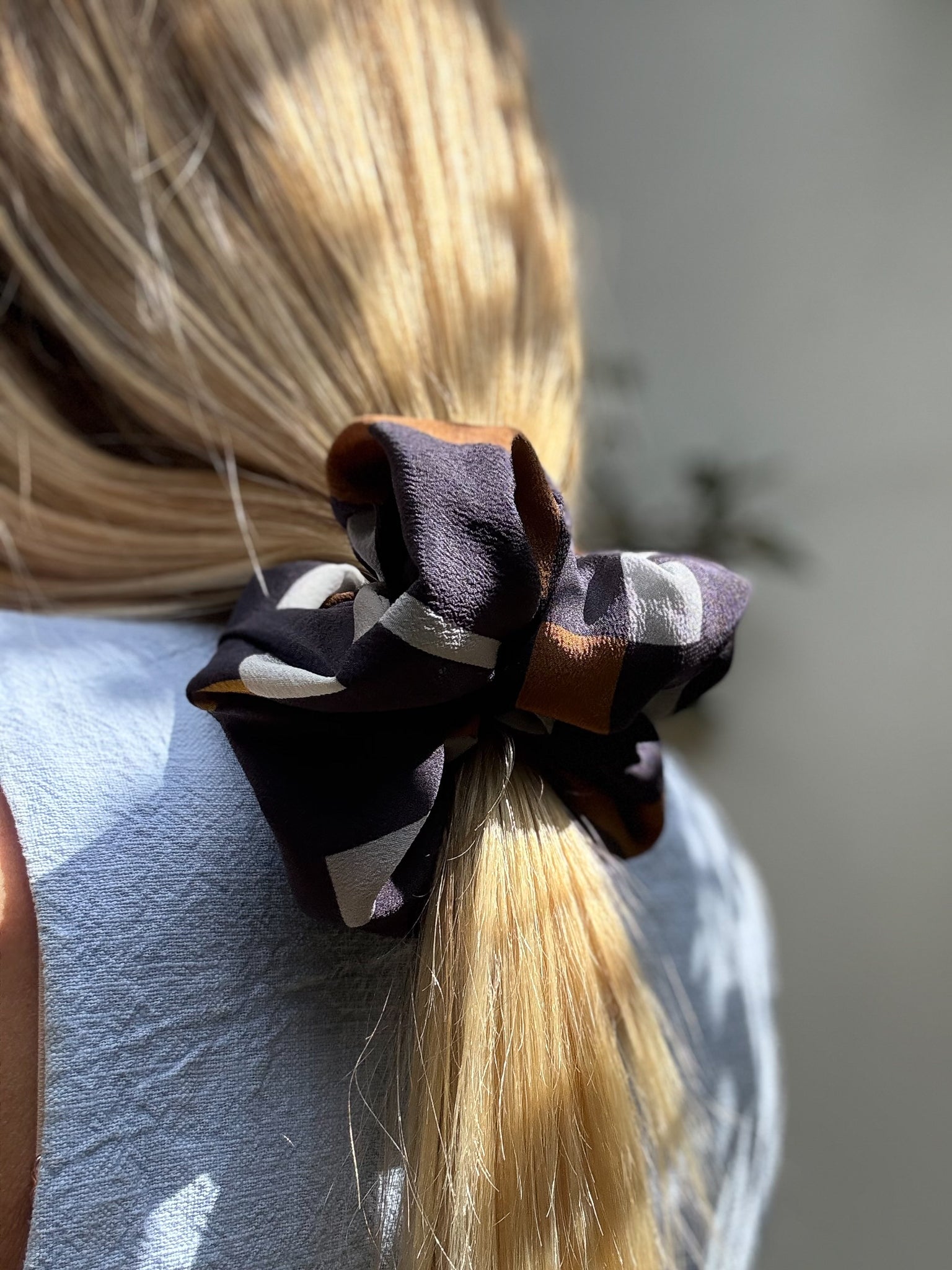 Close-up of a large hair scrunchie in a blonde ponytail with a blurred background