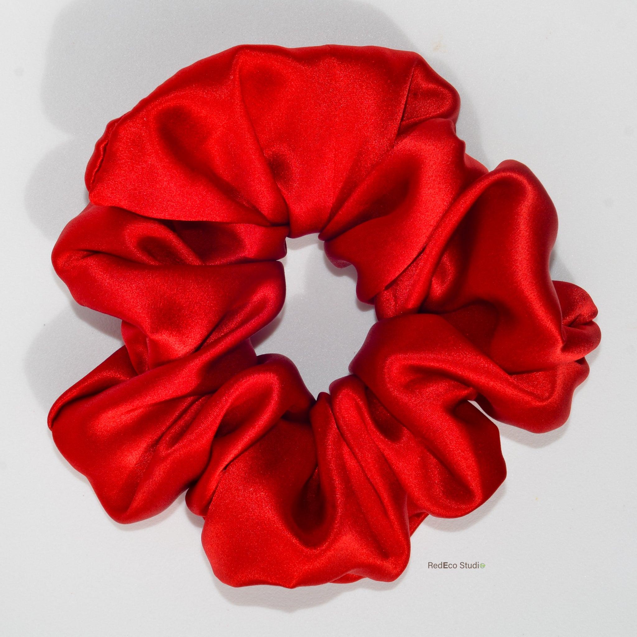 Red satin scrunchie on a light gray background