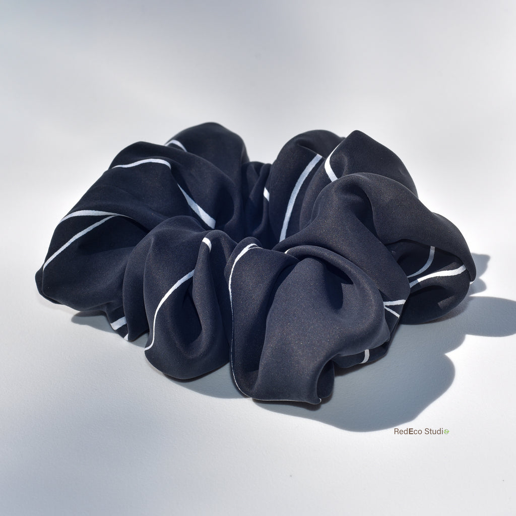 Black scrunchie with white accents on a light gray background