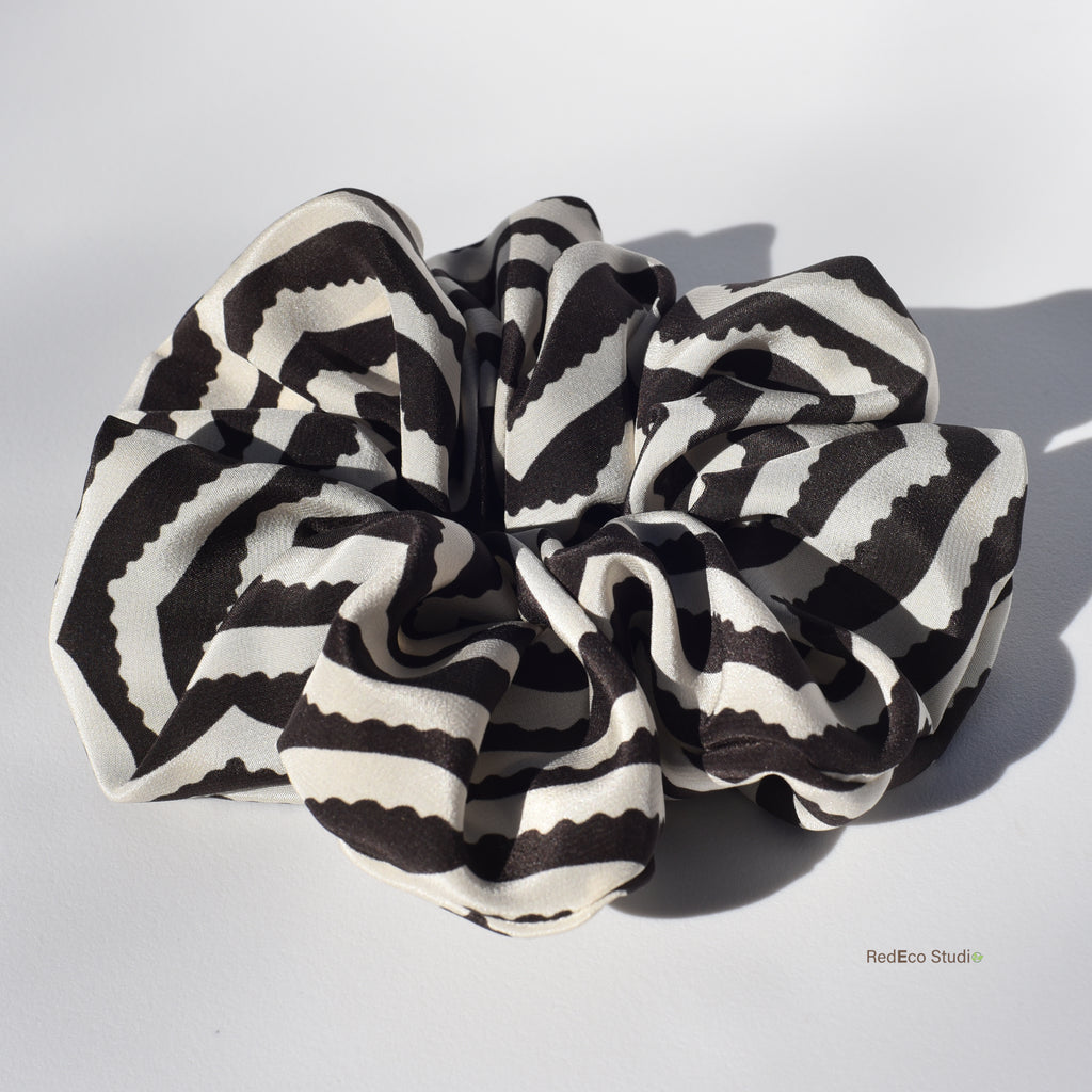 Large black and white striped silk scrunchie on a light gray background