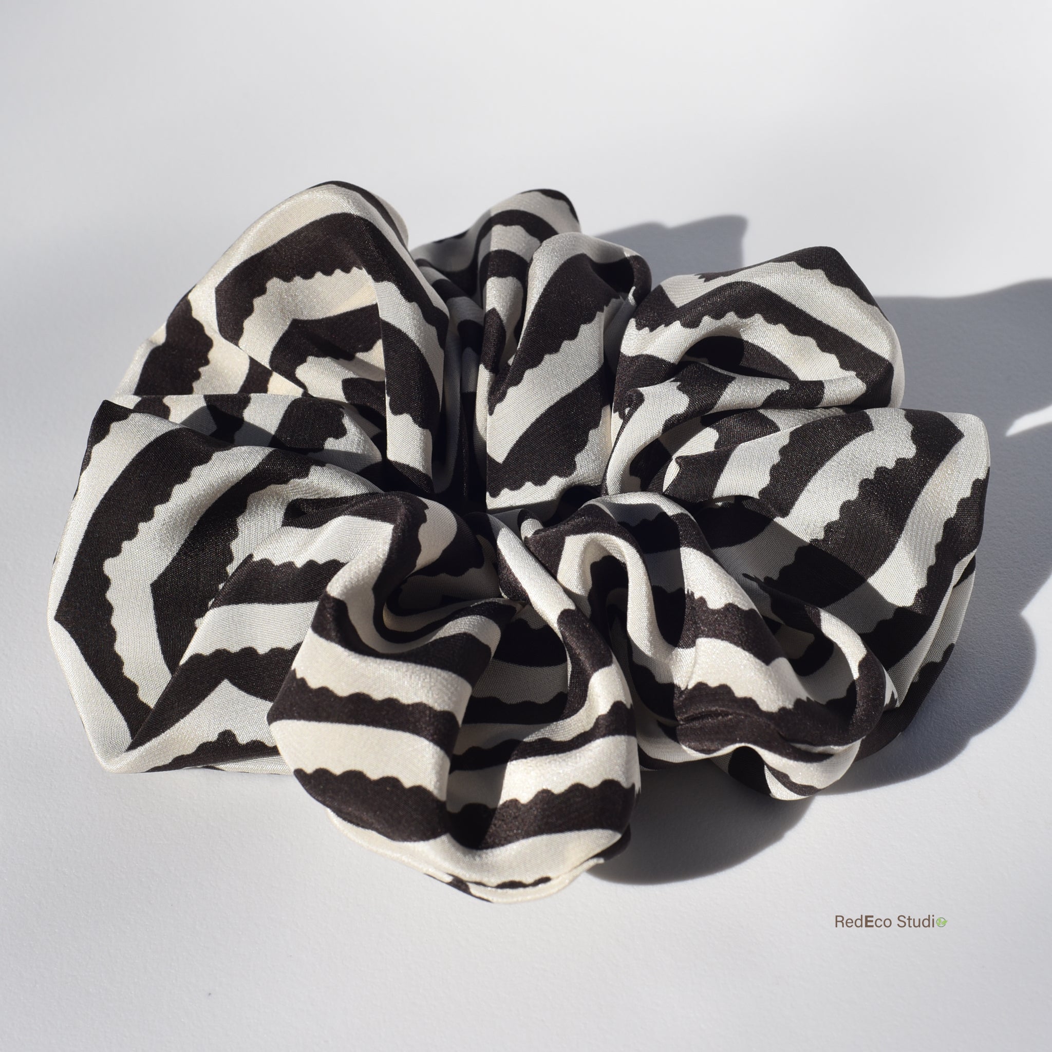 Large black and white striped silk scrunchie on a light gray background