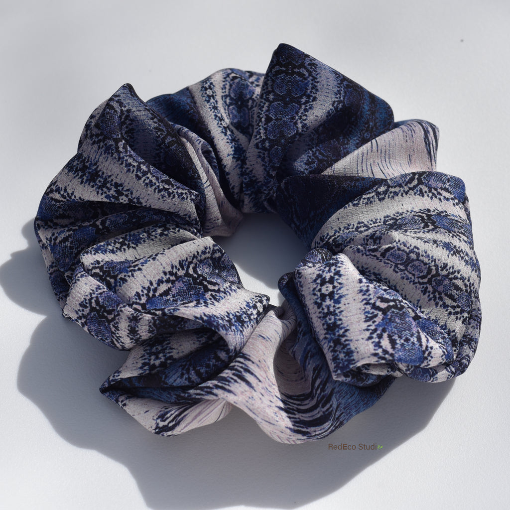 Blue and white patterned silk scrunchie on a light gray background