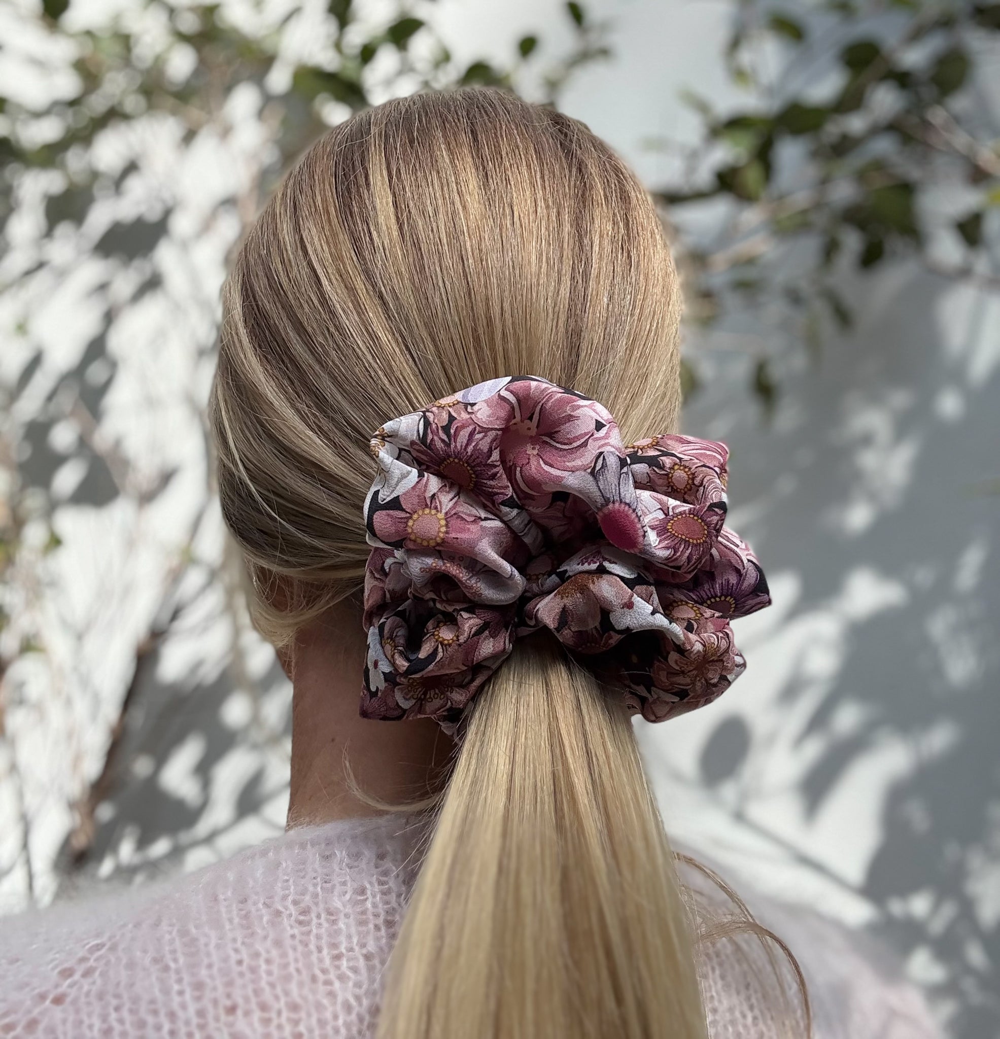 Person with floral silk scrunchie in hair against a natural background