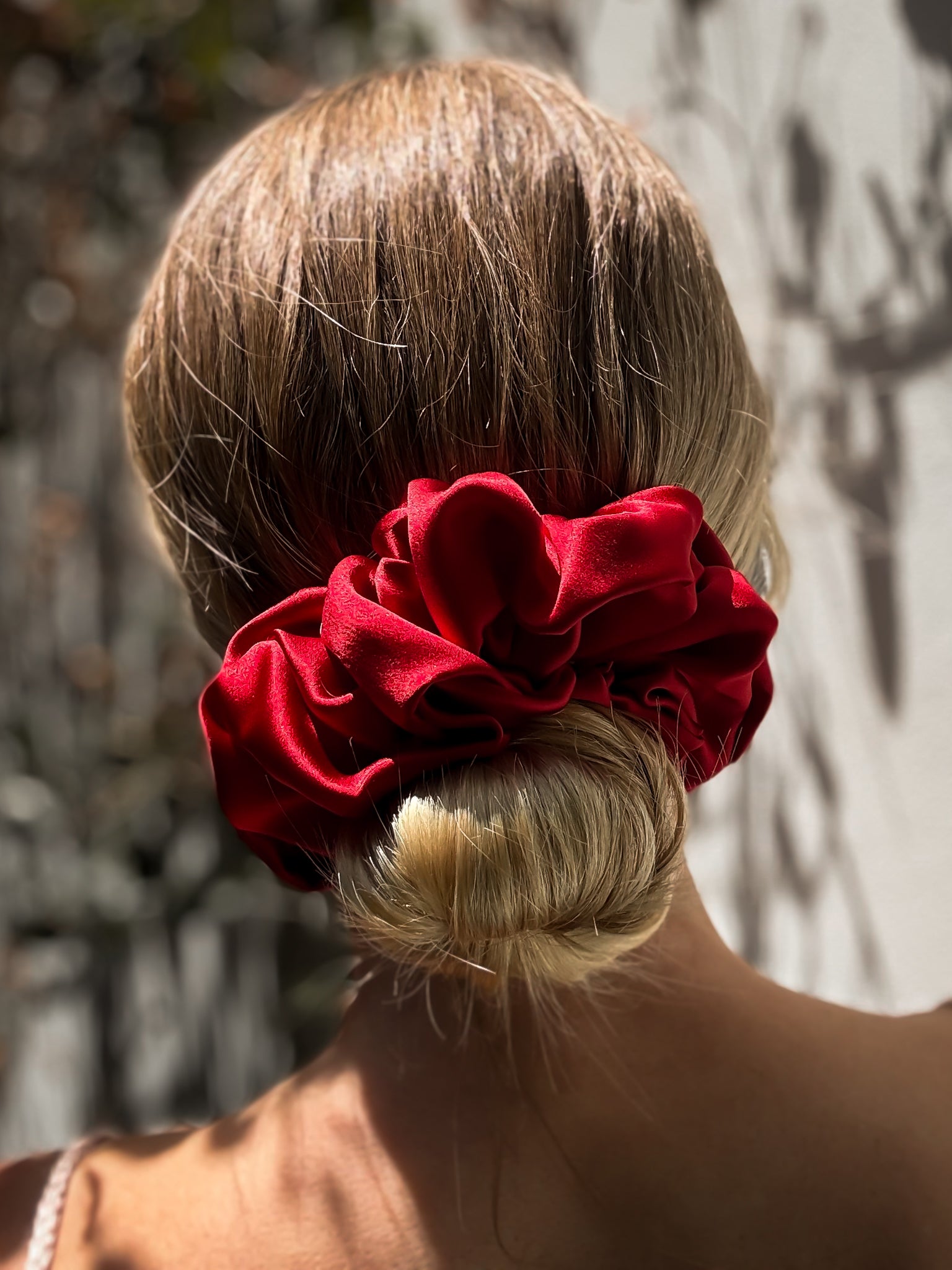 Red floral hair accessory in a bun against a natural background