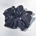 Large black scrunchie with white stripes on a light gray background